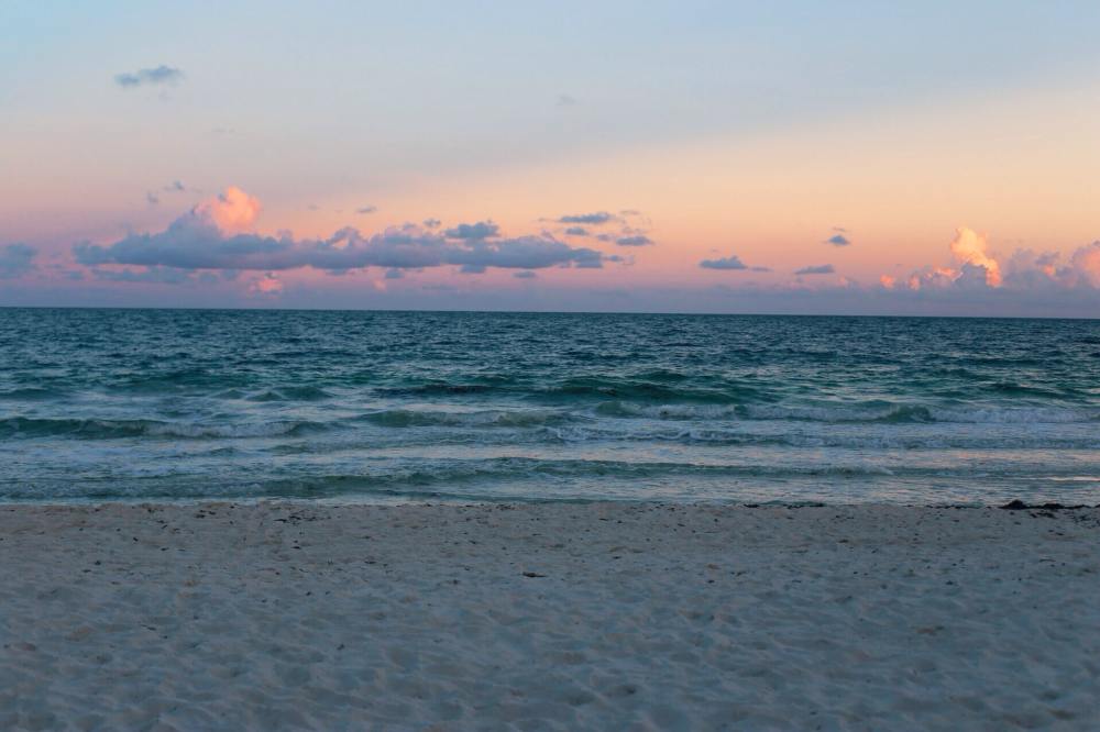 a sunset over a beach next to the ocean